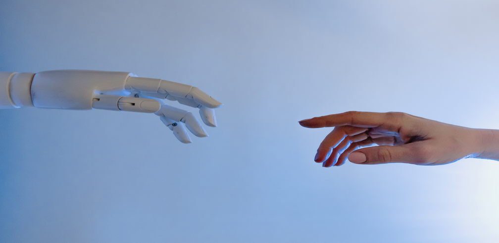 Image of a robotic and human hand reaching each other.