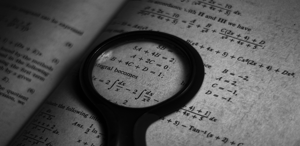 Image of a mathematics book with a magnifying glass.
